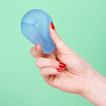 A hand squeezes the Dew Speks Gump Loop Gel Stress Ball.