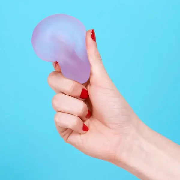 A hand squeezes the Mist Speks Gump Loop Gel Stress Ball.