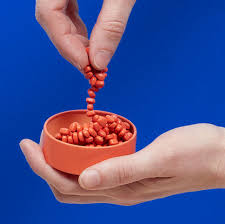 A hand holds onto a strand of Mini Matte Crags Magnetic Fidget Putty - Coral.