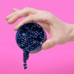 A hand tilts a tin of Mini Matte Crags Magnetic Fidget Putty - Indigo.