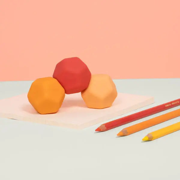 The three Orange Planes Odds Silicone Magnets are shaped in a rainbow next to three similarly colored pencils.