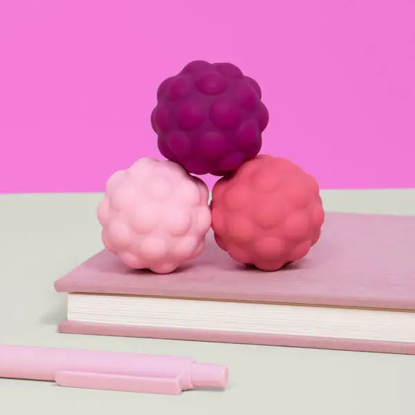 The Speks Odds Silicone Magnets sit in a triangle on top of a pink notebook.