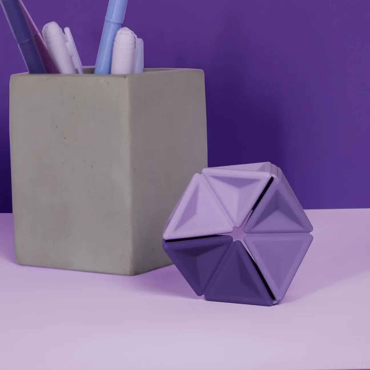 The Speks Violet Pivot Silicone Flexagon next to a cup full of purple pens.