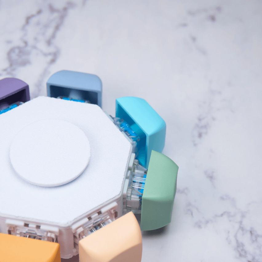 The Keyboard Fidget Spinner - 8 Keys, Rainbow, Silent on a marble tabletop.