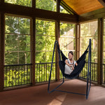 A woman leans back in the Polycotton Hammock Chair A-Frame Steel Stand.