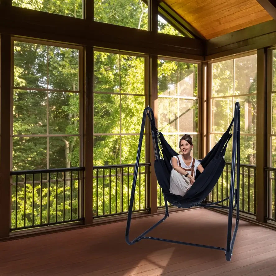 A woman leans back in the Polycotton Hammock Chair A-Frame Steel Stand.