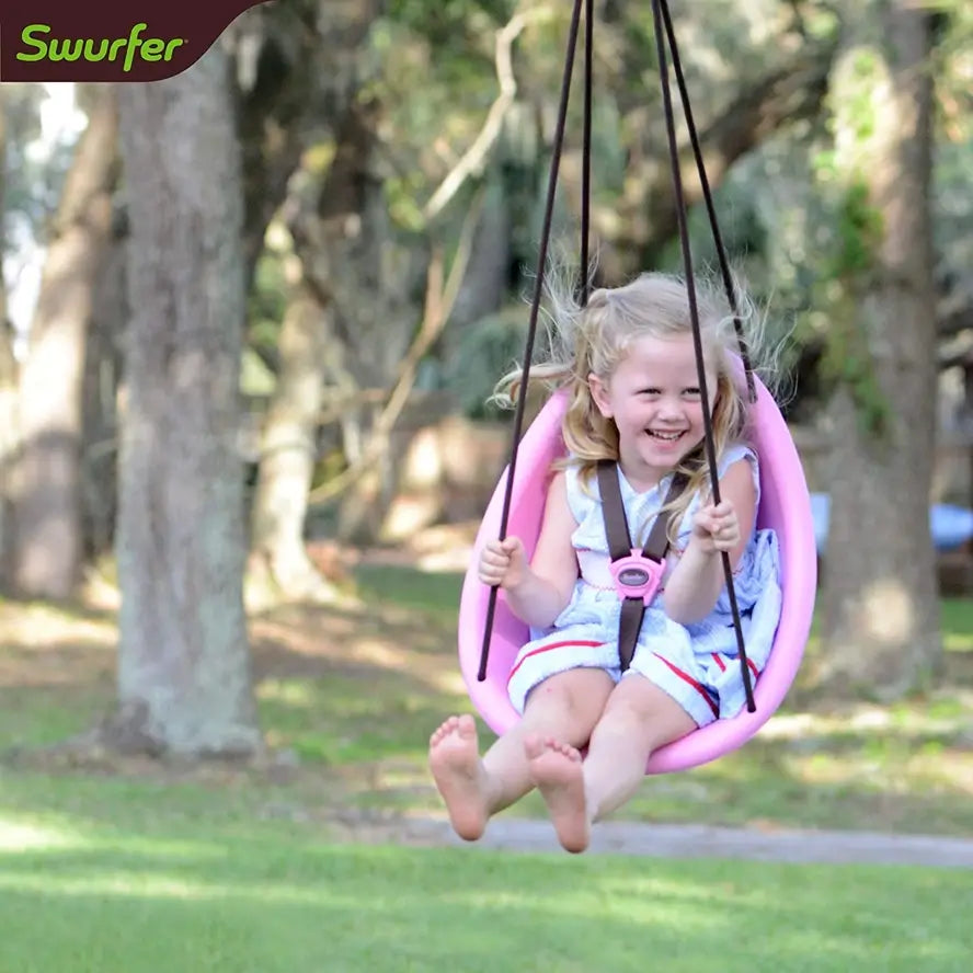 A toddler swings outside in the pink Swurfer Kiwi Baby and Toddler Swing.