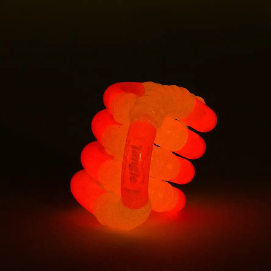 The pink Glow-in-the-Dark Tangle Jr. glowing.