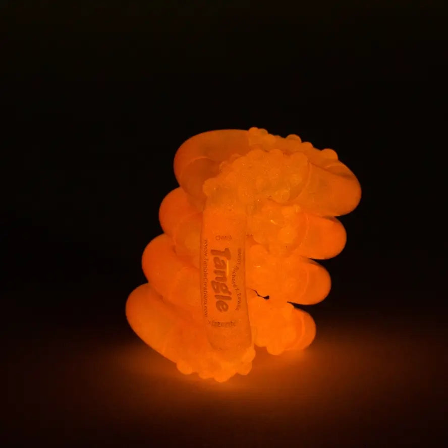 The orange Glow-in-the-Dark Tangle Jr. glowing.