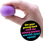 A hand squeezes a purple Teenie Nee Doh Fuzz Ball.