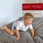 A child smiles as they pick themselves up from landing on the Terry Corduroy Children's Sensory Crash Pad.