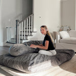 A woman uses her laptop while sitting on the Terry Corduroy Children's Sensory Crash Pad.