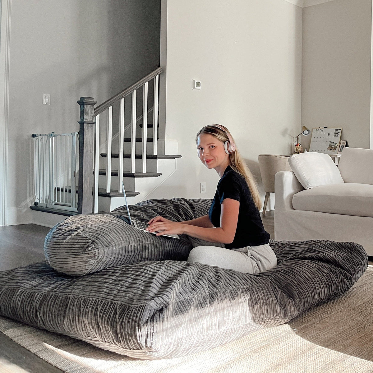 A woman uses her laptop while sitting on the Terry Corduroy Children's Sensory Crash Pad.