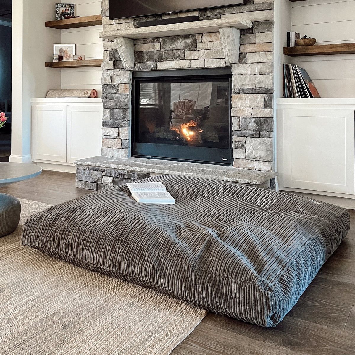 The Terry Corduroy Children's Sensory Crash Pad in front of a fireplace.