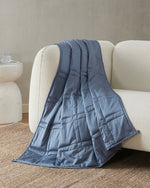 The Dusk Baloo Mini Weighted Blanket draped over a couch.