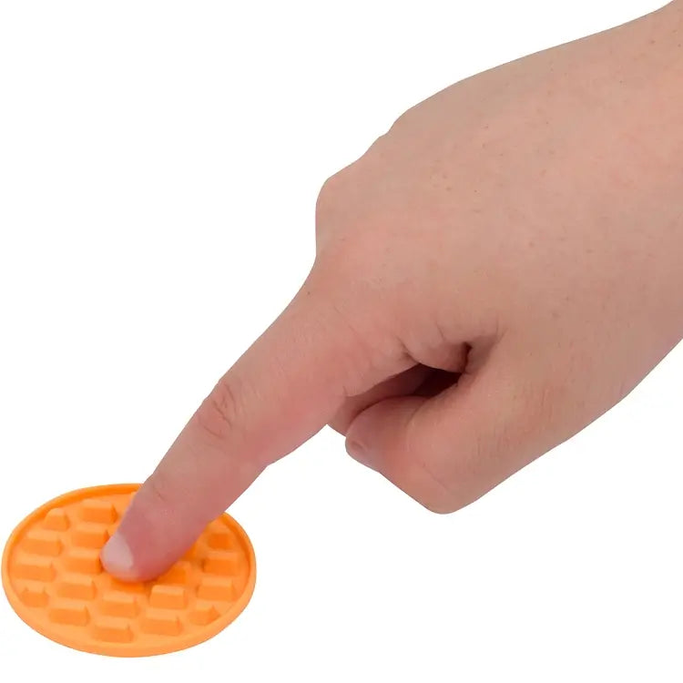 A finger presses down on an orange textured Silicone Zen Raised Dot Sensory Sticker.