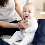 An adult uses the Pewter Tongue Depressor to look inside the mouth of a baby.