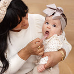An adult uses the Blush Tongue Depressor to look inside the mouth of a baby.