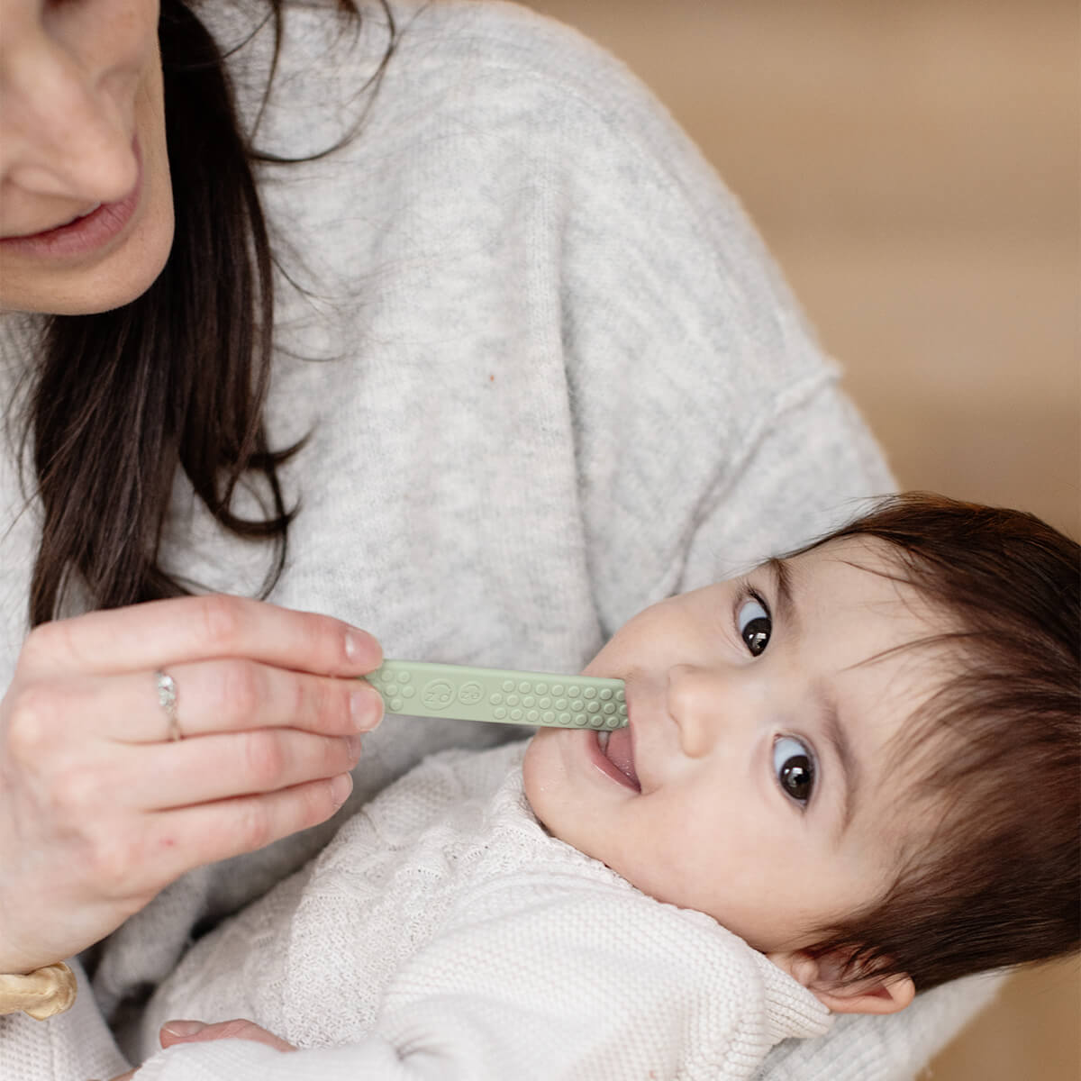 An adult uses a Sage Tongue Depressor to examine the inside of a babies mouth.
