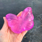 A hand holds the pink  Super Duper Sugar Squisher Butterfly.