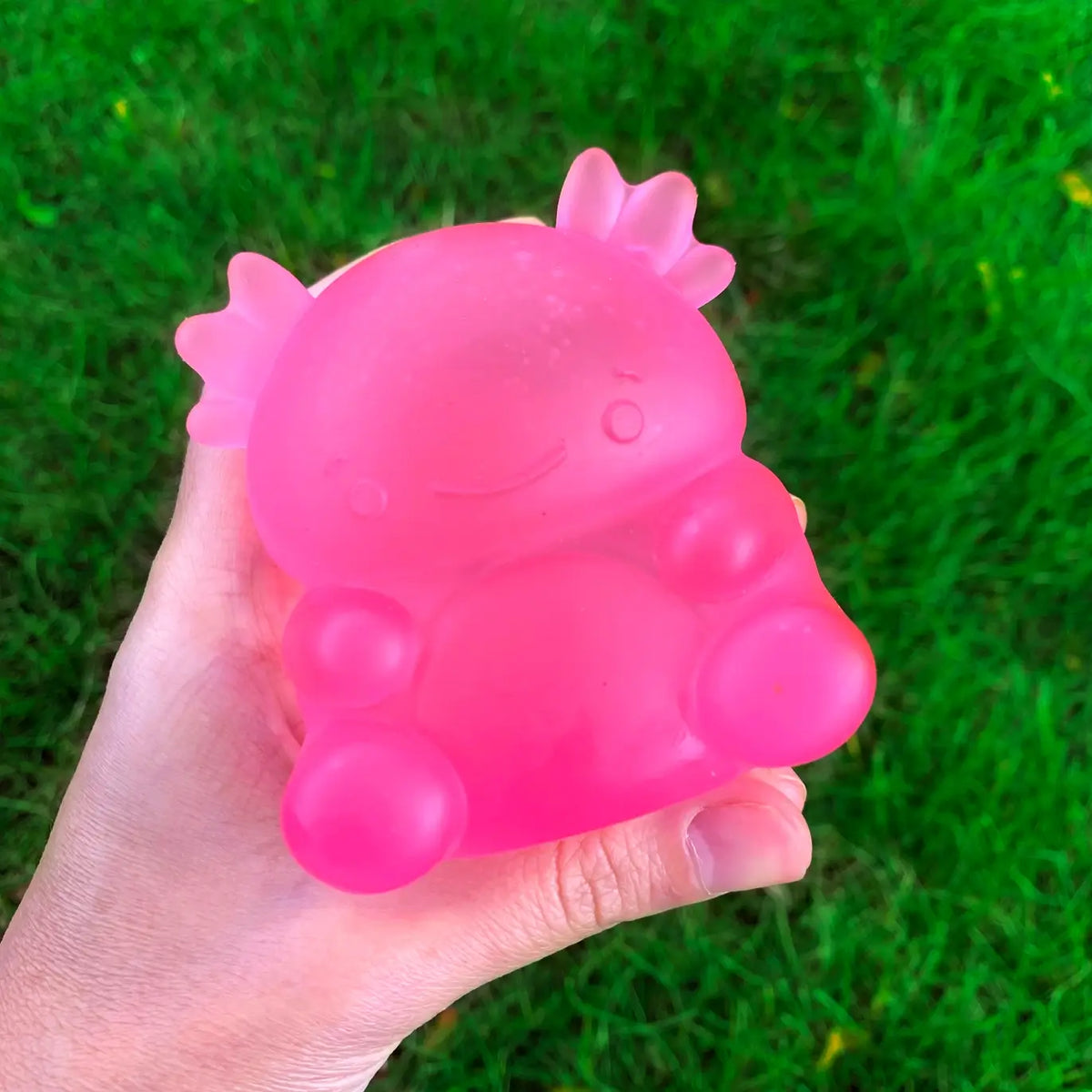 A hand holds the pink Super Duper Sugar Squishers Axolotl.