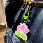 The "I Will Cry On This Hill" Keychain attached to a leather bag's zipper.