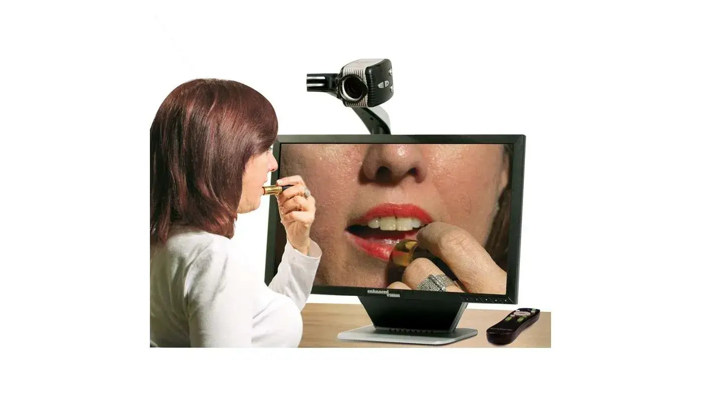 A woman sits in front of the Acrobat Ultra HD Low Vision Magnifier; she is putting on lipstick and the screen is showing a magnification of her face.