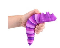 The purple Wiggle Sensory Dinosaur being held by a hand with light skin tone.