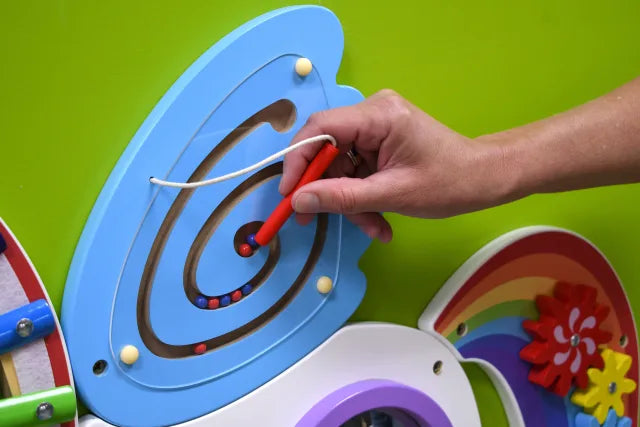 A hand with light skin tone plays with the magnetic puzzle on the Unicorn Activity Wall Panels.