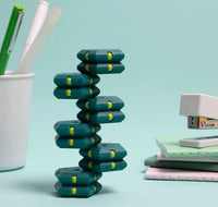 The Monstera Geode Pop stands independently next to a cup holding three pens and a stapler stacked on top of four small notebooks.
