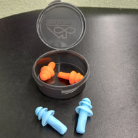 The Sensory Tool House Limited Edition Noise Reducing Ear Plugs case is open and the orange pair is inside. The blue pair is sitting in front of the case.