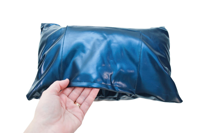 An adult hand with light skin tone shows the pocket crevice on the front of the Abilitations Vinyl Vibrating Weighted Lap Pad.