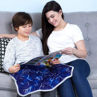 A child and an adult are sitting on a couch looking at a magazine together. The child has a Weighted Lap Pad on their lap.