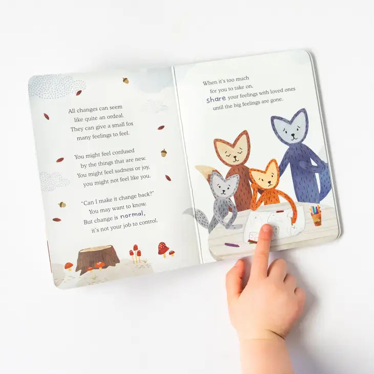 A small hand with light skin tone points at an illustration inside of the board book for Slumberkins Woodland Fox Kin.