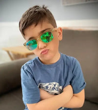 A child with medium light skin tone and short brown hair has their arms crossed and is making a pouty face. They are wearing Children's Polarized Sunglasses.