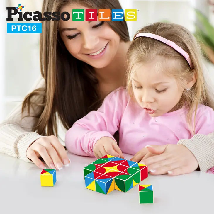 An adult with light skin tone and long brown hair sits behind a child with light skin tone and long light brown hair.  The child is looking down at a formation made by the Infinite Magnetic Cube Set.