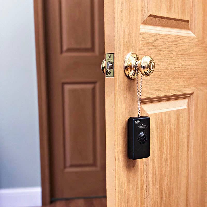 The 2-in-1 Door Alarm and Personal Alarm System hanging from a door.