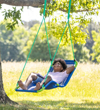 A child with dark skin tone and a black afro lays back in the Lounge Chair Swing. They are smiling and holding a book in their lap, one arm under their neck.