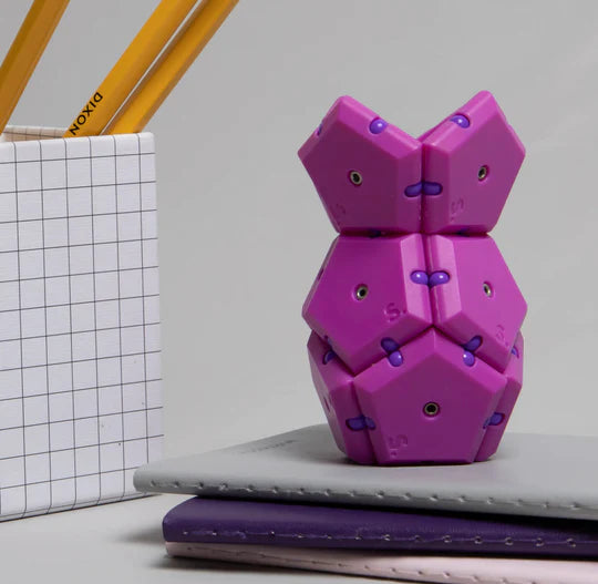 The Razzle Geode Pop is built into a tiny structure and sits on top of three notebooks, next to a pencil holder with three number 2 pencils.