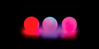Three Glow.0 Juggling Balls illuminated with different colors.