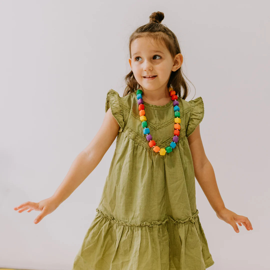 A child with light skin tone and long brown hair is looking up and to the right while modeling the Princess and the Peak Necklace.