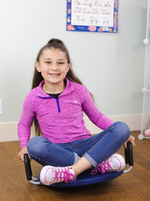 A child with light skin and long brown hair is sitting on the Wiggle Wobble Rock and Twist Board. They are sitting criss cross applesauce and holding onto the two foam covered handles. 