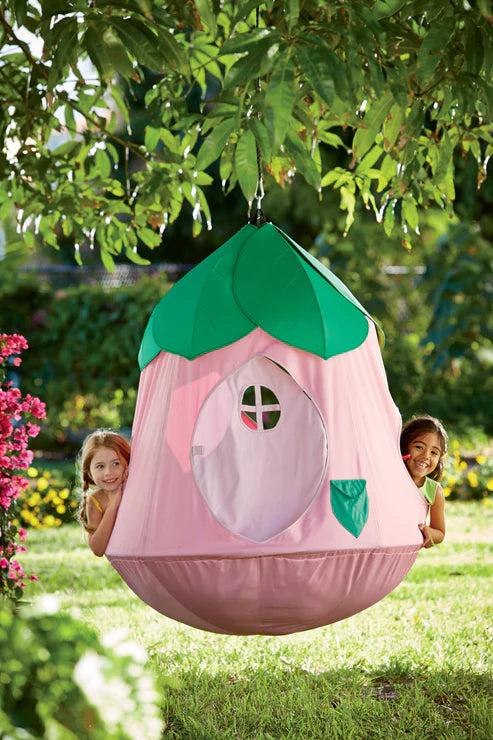 A Cozy Posy HugglePod hangs in a yard with two children peeking their heads out on either side.