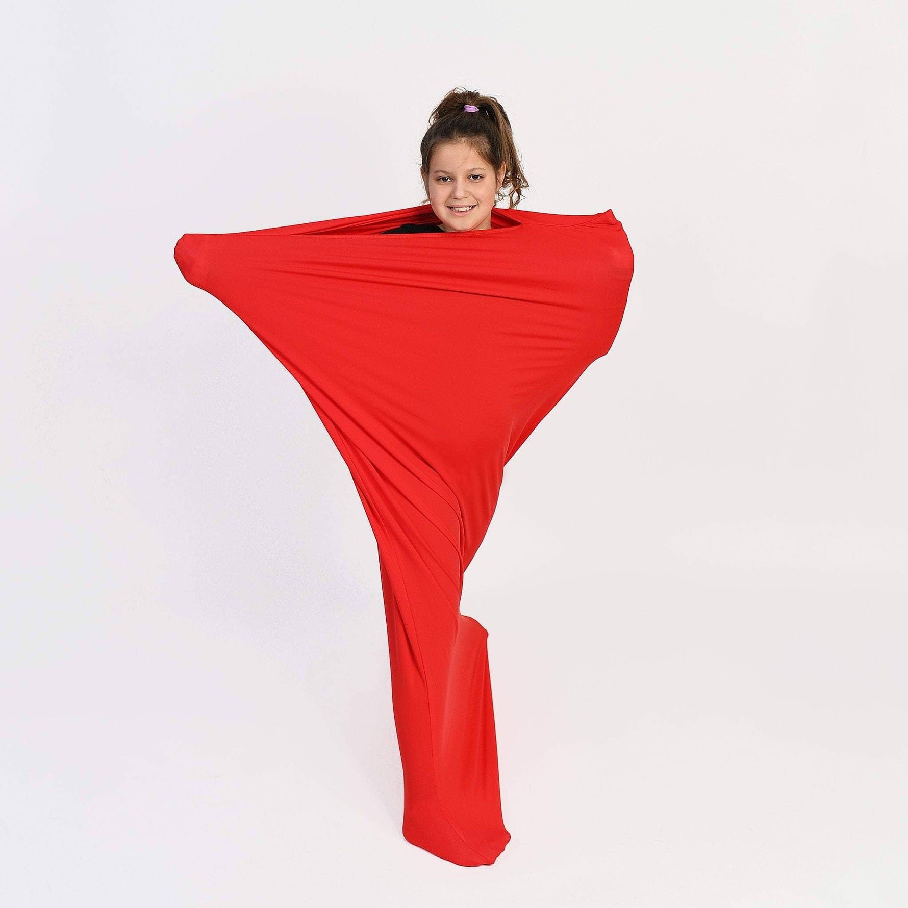 A child with light skin tone and brown hair pulled up into a pony tail is standing in a Red Body Sock with their arms outstretched.