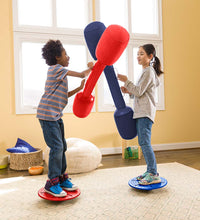 Two children stand on separate balance boards and hold up the inflatable Jousts. The jousts are meeting in the middle.