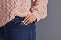 A hand with light skin tone places a TouchPoint into a jean pants pocket.