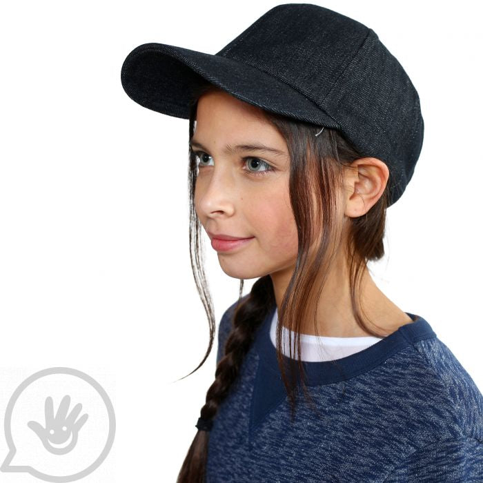 A child with light skin and a long dark brown braid is wearing the Denim Weighted Baseball Cap.