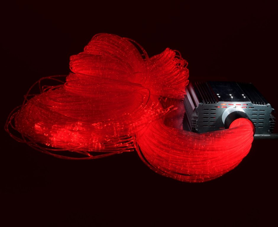 A thread of Fiber Optic Tails glow red. They are plugged into a light source.
