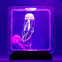 A display of one yellow and one pink jellyfish in a darker setting to illustrate the LED glow.