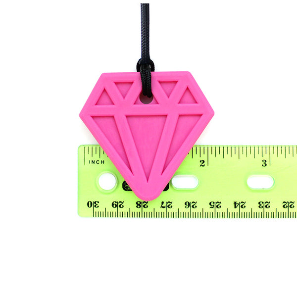 The pink Diamond Chewable Jewel Necklace sits on top of a ruler and measures a little over 2" across.
